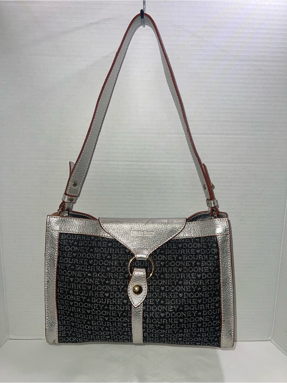 This vintage Dooney & Bourke shoulder bag features a signature logo